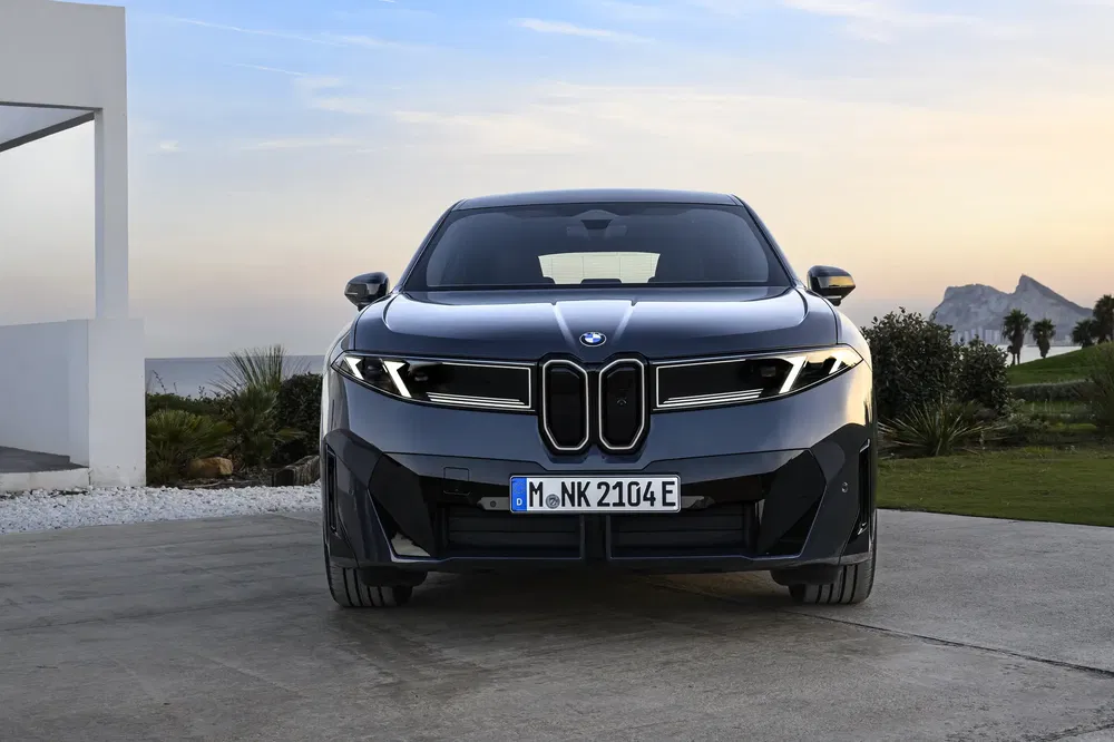 BMW i5 zwart vooraanzicht bij zonsondergang, moderne natuurlijke omgeving.