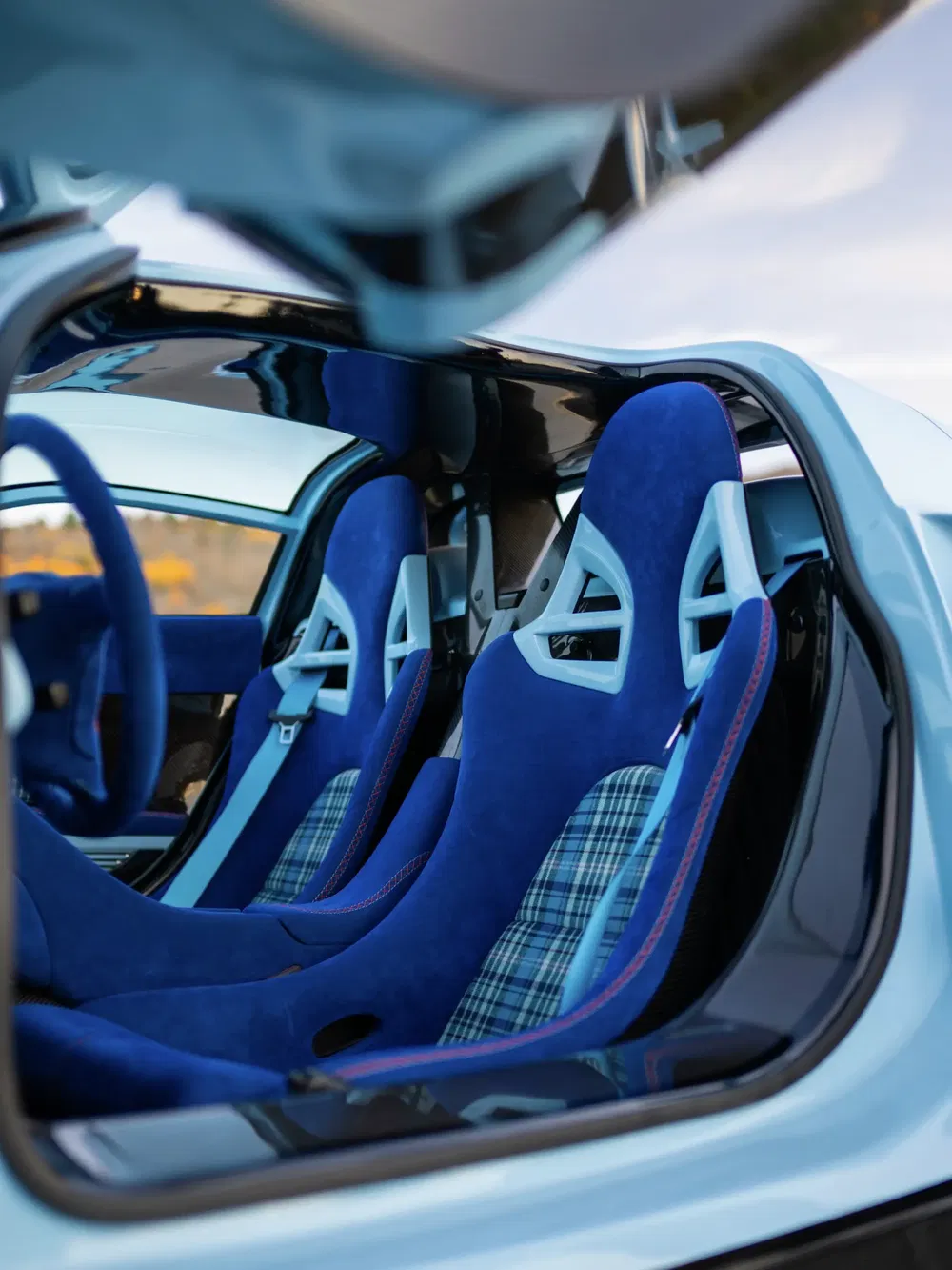 Intérieur de voiture sport avec sièges baquets bleus en tissu à carreaux.