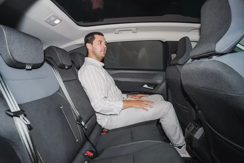 Man zit achterin een moderne compacte auto met ruim en stijlvol interieur.