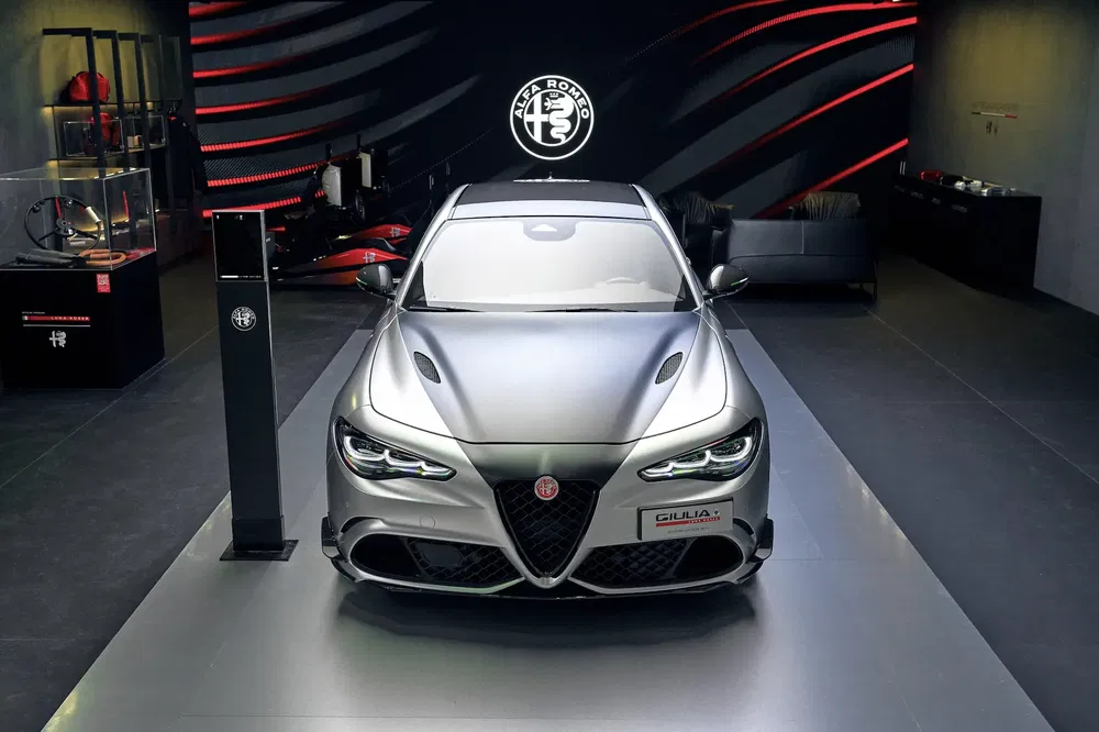 Alfa Romeo Giulia tentoongesteld in een moderne zaal met rode verlichting en stijlvolle meubelen.