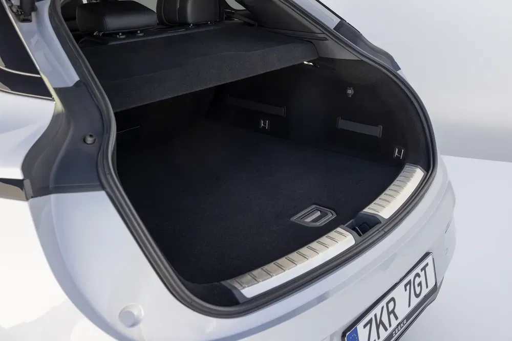 Coffre spacieux d'une voiture familiale blanche, avec sièges arrière rabattables.