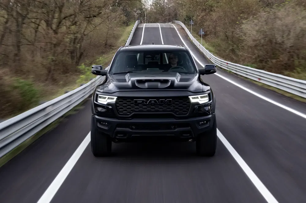 Zwarte RAM 1500 TRX rijdt op kronkelende weg omringd door bomen.