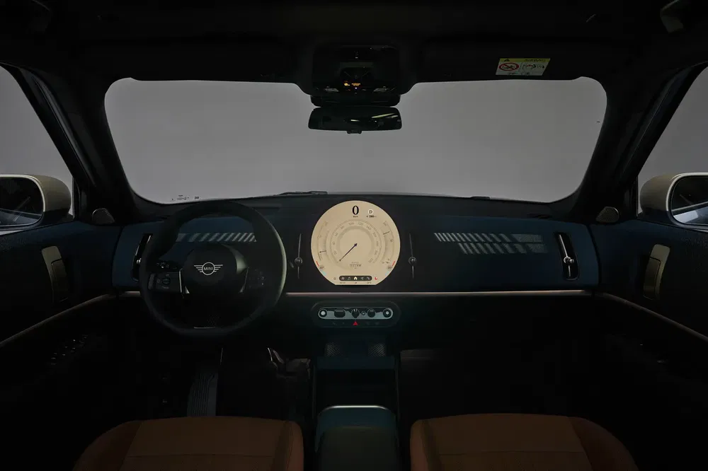 Intérieur d'une Mini moderne avec tableau de bord numérique rond et volant emblématique.