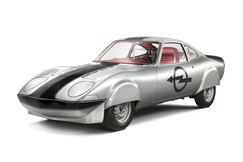 Zilverkleurige Opel GT elektrische prototype uit 1971, gestroomlijnd ontwerp, rood interieur.