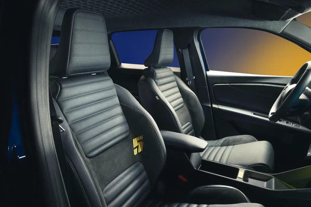 Moderne interieur van de Renault 5 met zwarte lederen stoelen en strak dashboard.