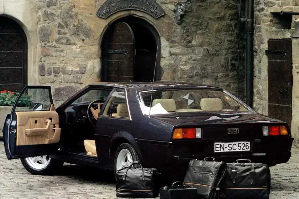 Zwarte Gillet Vertigo met open deur, voor middeleeuws stenen gebouw.