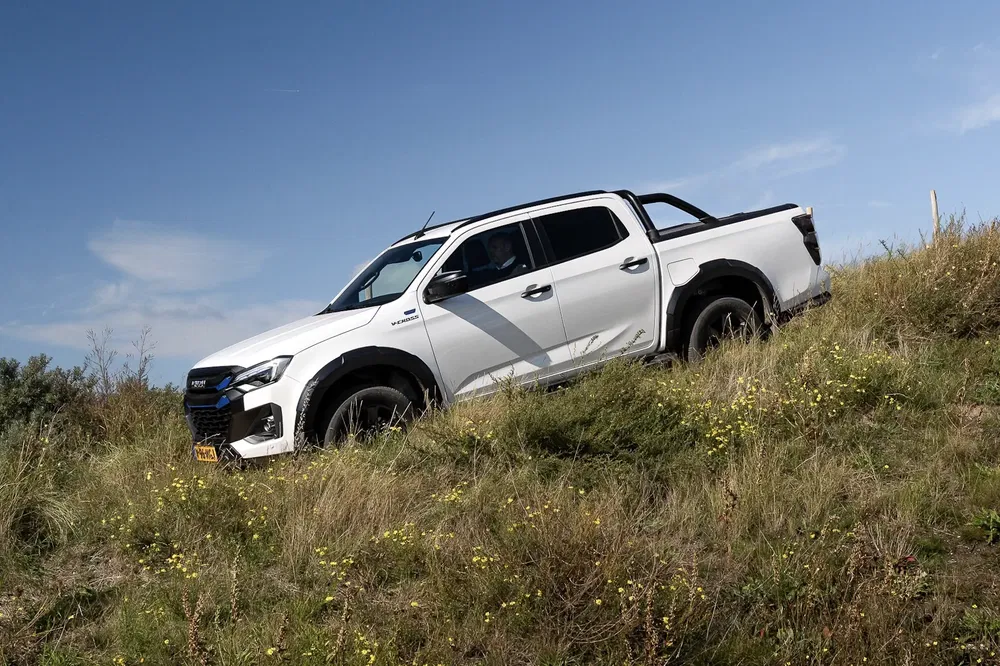 {"fr":"Isuzu D-Max blanc descendant une colline herbeuse sous un ciel bleu.","nl":"Witte Isuzu D-Max rijdt heuvel af in grasland onder blauwe lucht."}