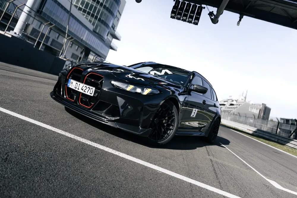 Zwarte BMW M4 op racecircuit, dynamisch vooraanzicht.