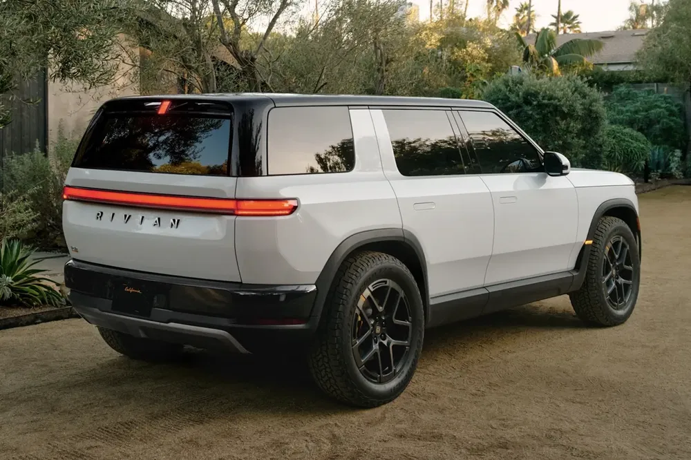 SUV électrique Rivian R1S blanc garé, design élégant et futuriste, au milieu de la nature.