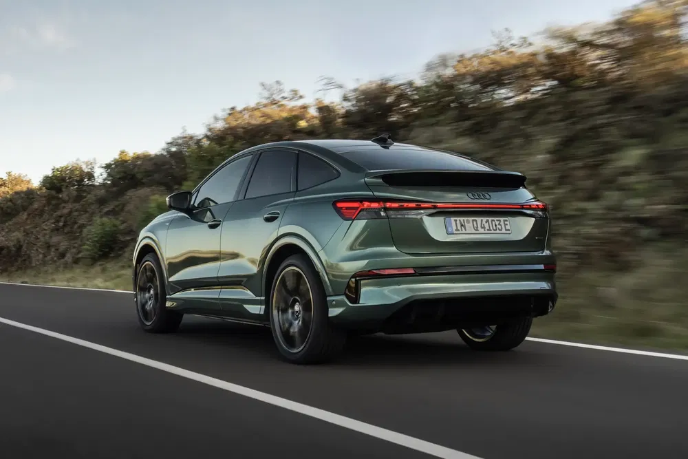 Audi Q4 e-tron vert roulant sur route dégagée, arrière dynamique.