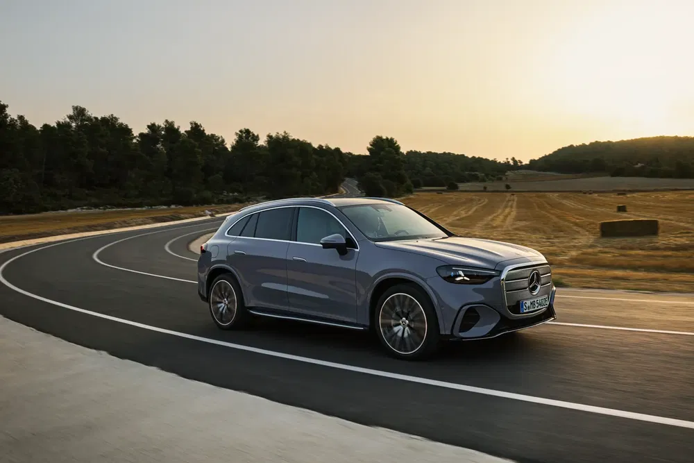 Mercedes-Benz SUV op bochtige weg bij zonsondergang, stijlvol ontwerp en dynamische prestaties.
