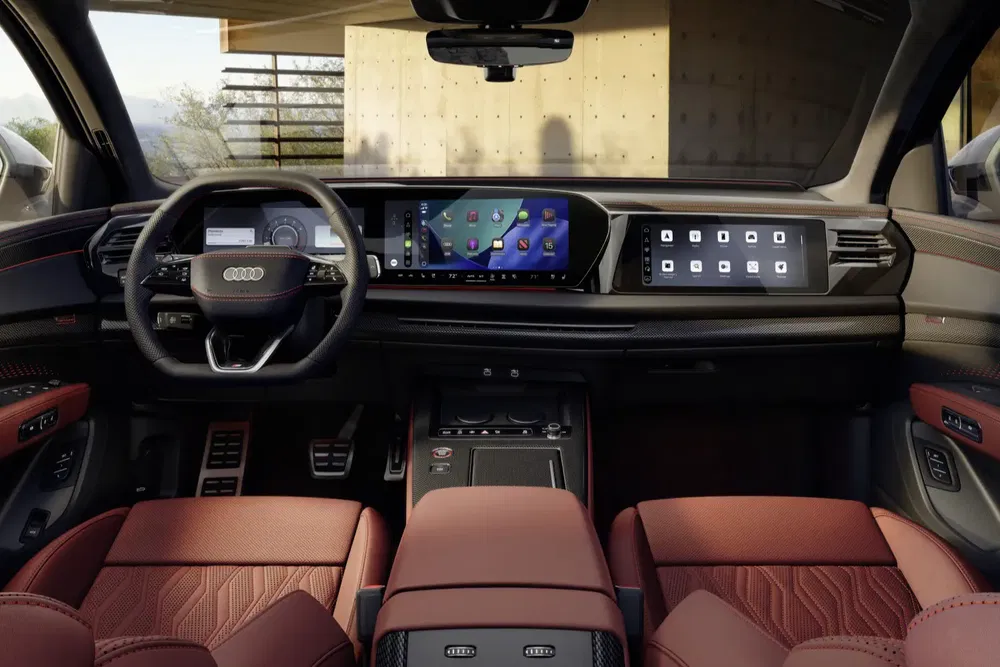 Intérieur moderne de l'Audi Q6 e-tron avec tableau de bord numérique et sièges en cuir rouge.