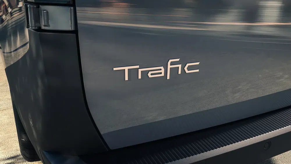 Arrière du Renault Trafic avec badge distinctif en conditions ensoleillées.