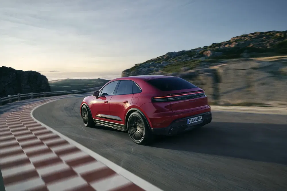Porsche Cayenne rouge 2024 sur route sinueuse, paysage montagneux en arrière-plan.