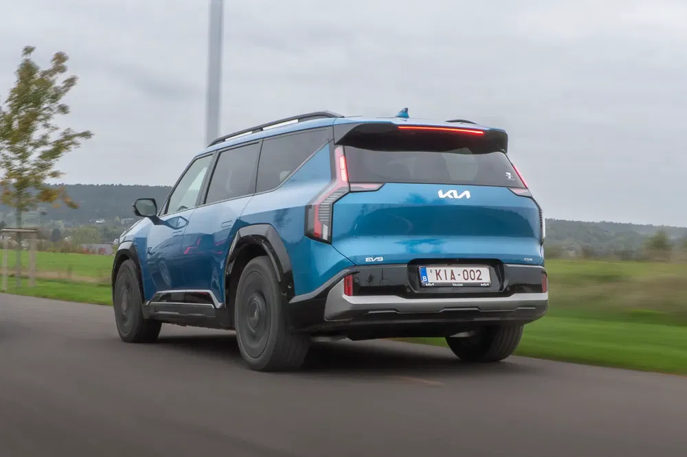 Kia EV9 bleu sur route, paysage en arrière-plan, design moderne et dynamique.