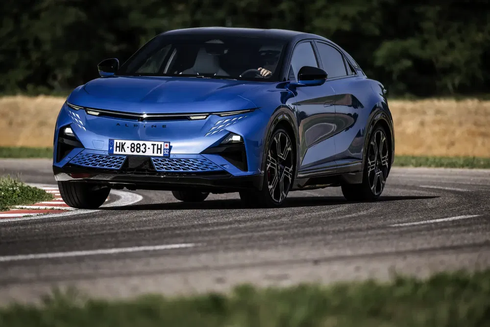 Alpine électrique bleue sur piste, virage à haute vitesse, arrière-plan flou.