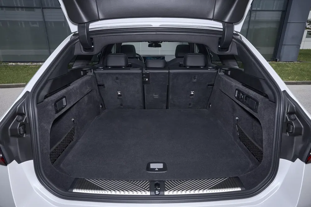 Coffre spacieux d'une BMW i5, sièges arrière rabattus pour plus de rangement.
