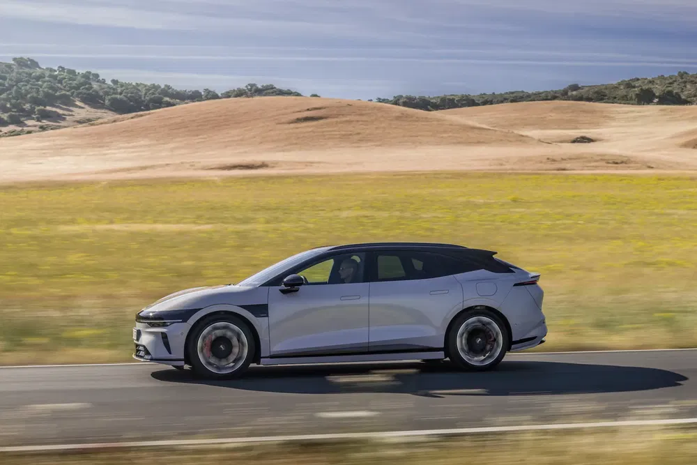 Lucid Air roulant sur une route panoramique avec des collines en arrière-plan.