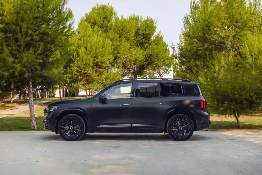 Zwarte elektrische SUV voor groene bomen, perfect voor duurzame autoblog.