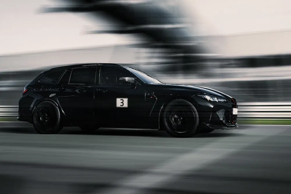 BMW M-wagen racet op circuit, bewegingsonscherpte, stijlvolle zwarte carrosserie.