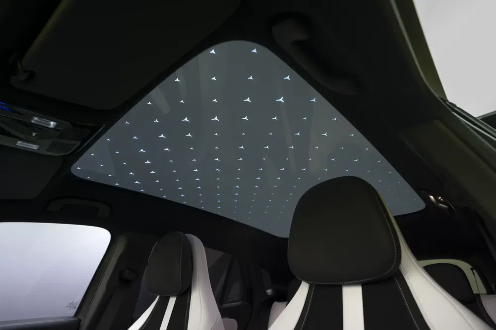 Toit panoramique avec motif étoilé, intérieur luxueux d'une voiture moderne.