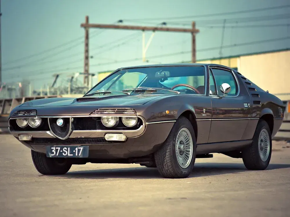 Voiture classique Alfa Romeo Montreal marron garée, design emblématique aux doubles phares distinctifs.