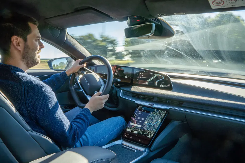 Intérieur d'une voiture électrique moderne avec tableau de bord numérique, conducteur concentré au volant.