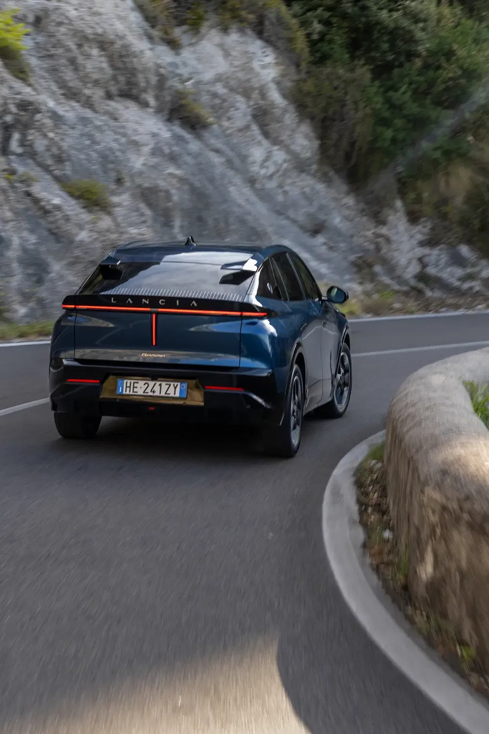 Voiture Lancia moderne sur une route sinueuse de montagne, arrière avec détails de feu LED.