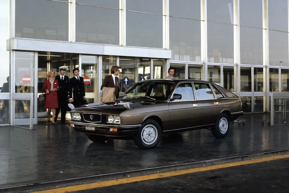 Lancia Gamma 1980, une voiture classique sortant de l'aéroport, entourée de personnel.