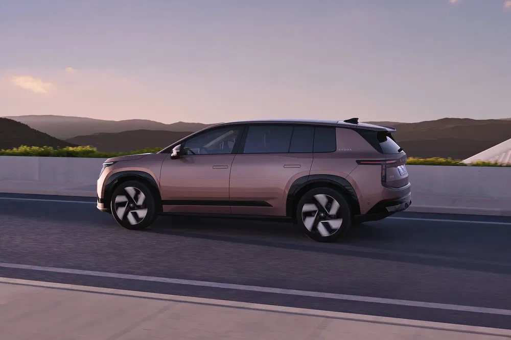 SUV électrique Zeekr 009 roule sur route au crépuscule, paysage montagneux en arrière-plan.