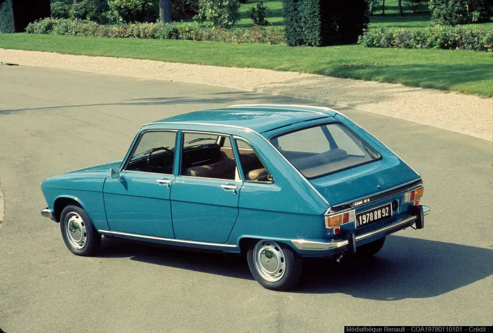 Renault 16 bleue des années 1970 roulant sur une route bordée de pelouse verte.