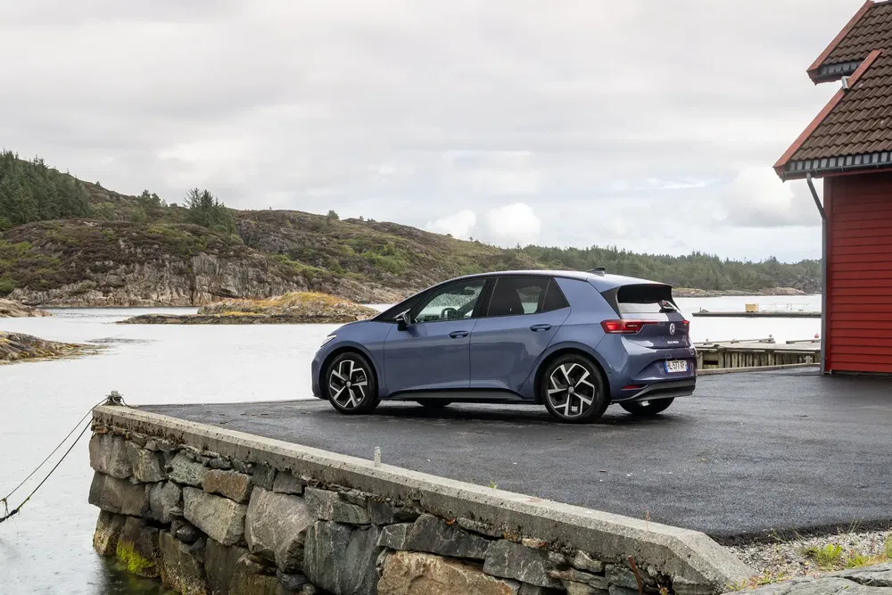 Blauwe Volkswagen ID.3 geparkeerd bij een schilderachtig kusthuis.