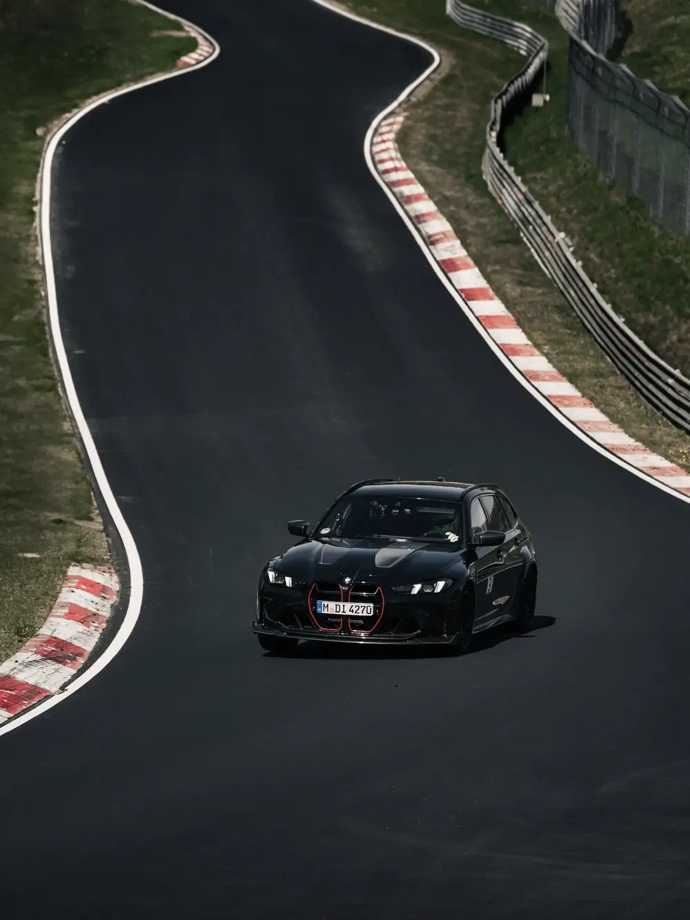 Zwarte BMW op Nürburgring-circuit, scherpe bocht op asfaltbaan.