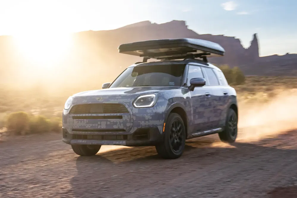 Mini Countryman off-road rijdend in de woestijn bij gouden licht met een bagagedrager.