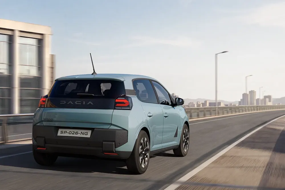 Dacia Spring électrique roulant sur une route en ville, design moderne et compact.