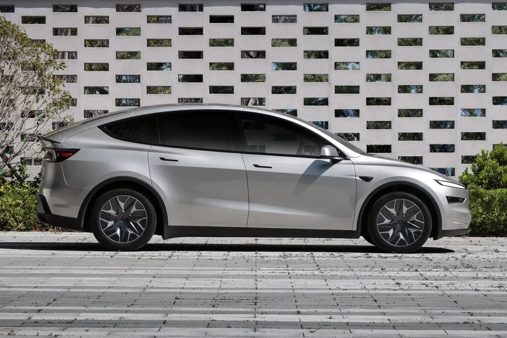 Tesla Model Y blanche garée devant un mur texturé, design élégant et moderne.