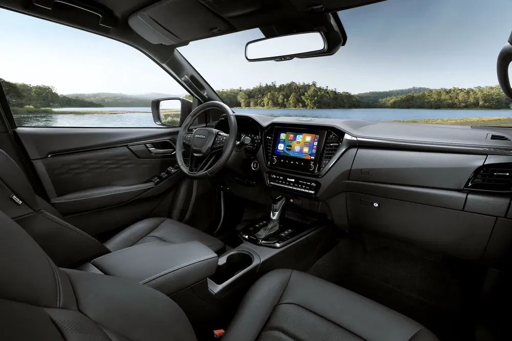 Intérieur du véhicule Isuzu moderne avec écran tactile, vue sur un lac pittoresque.