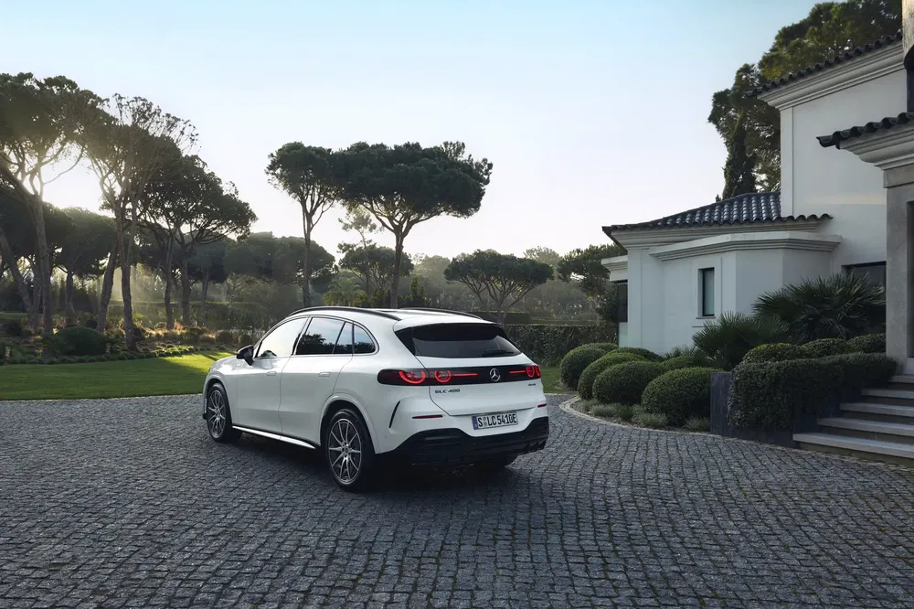 Mercedes-Benz EQC blanc garé sur une allée pavée près d'une maison moderne.