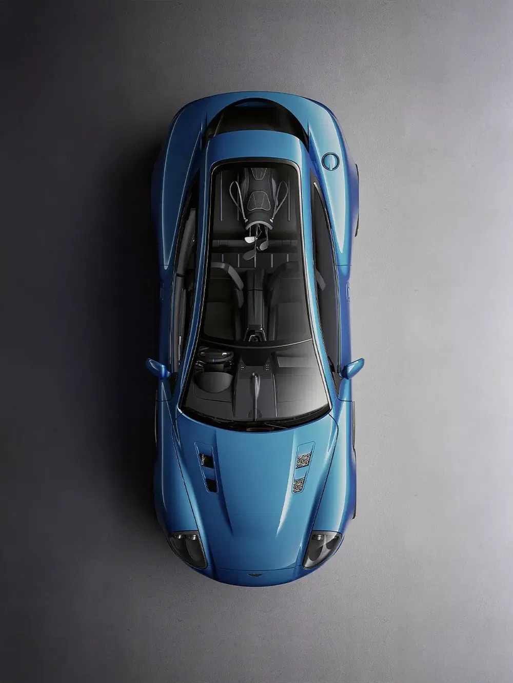 Vue aérienne d'une Aston Martin bleue élégante sur fond gris.