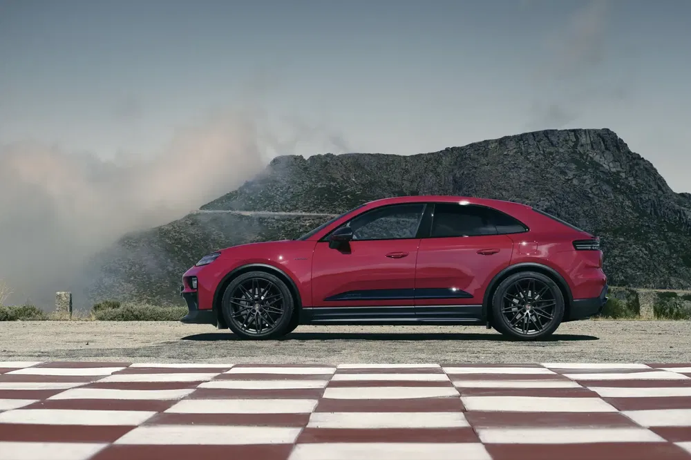 Porsche Cayenne rouge sur piste avec montagnes en arrière-plan, paysage spectaculaire.