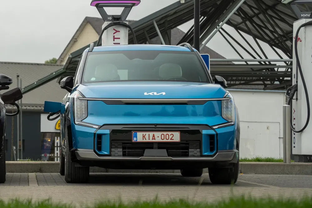 Kia EV9 bleu à une station de recharge électrique Ionity, plaque KIA 002.