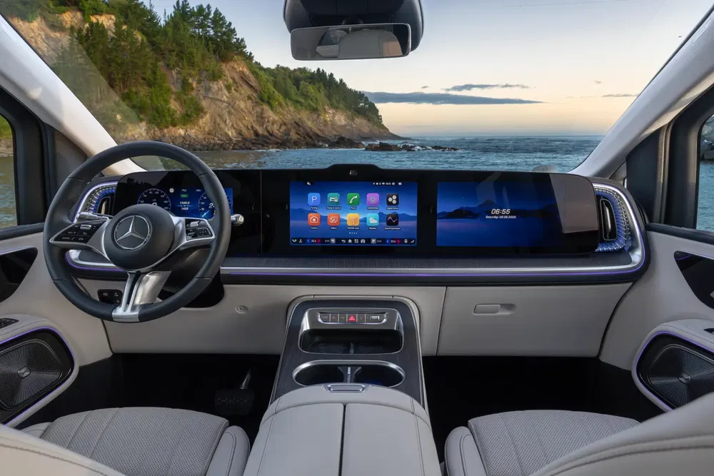 Intérieur de la Mercedes-Benz EQS avec écran numérique, vue sur océan et falaises.
