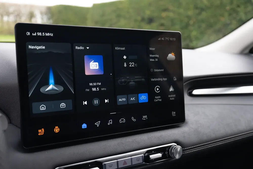 Écran tactile de voiture moderne affichant navigation, radio et contrôle climatique à l'intérieur d'un véhicule.