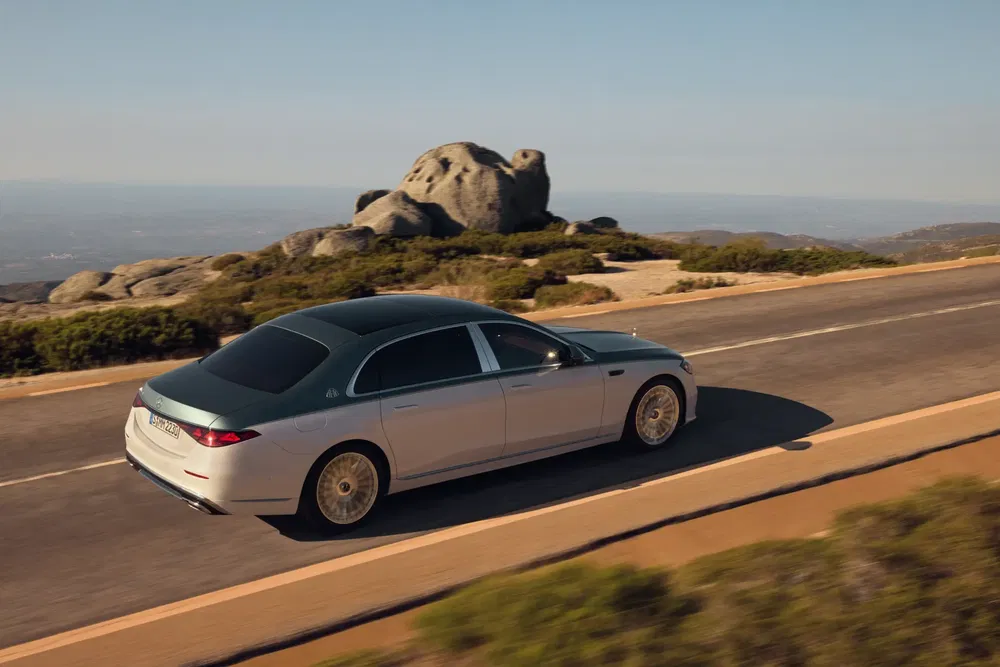 Mercedes-Maybach Classe S sur route côtière, paysage rocheux en arrière-plan.