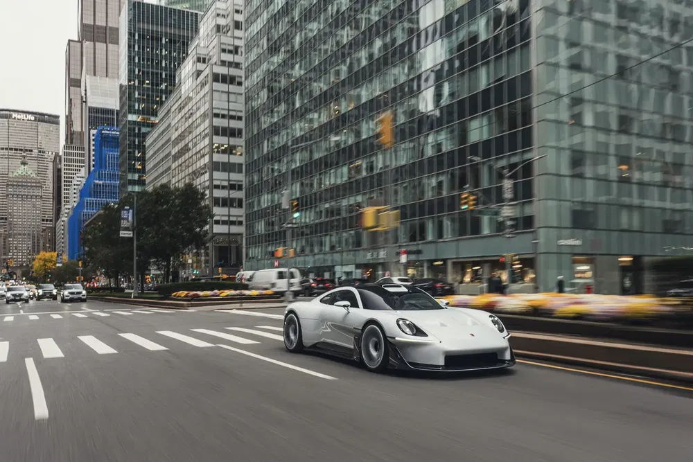 Zilveren Porsche-auto rijdt door stedelijke straat omringd door moderne wolkenkrabbers.
