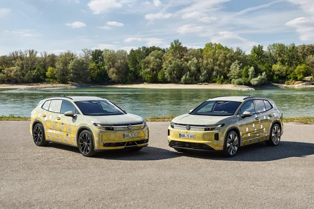 Deux prototypes Volkswagen SUVs électriques camouflés stationnés près d'une rivière.
