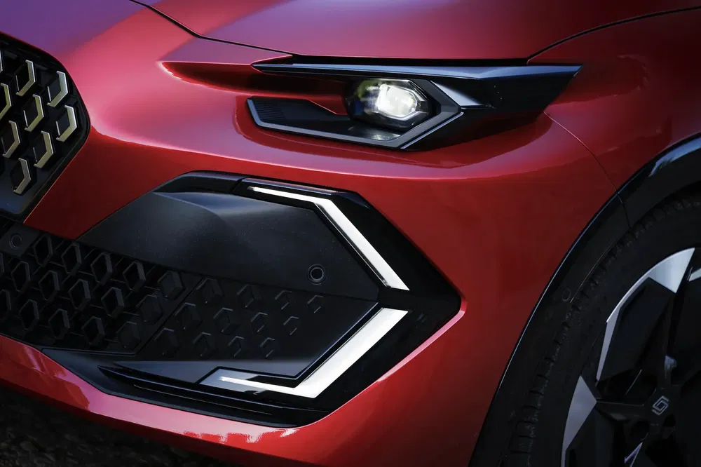 Gros plan sur la calandre et le phare d'une Alfa Romeo Tonale rouge.