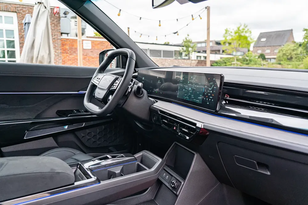 Moderne auto-interieur met touchscreen en stijlvol stuurwiel in stedelijke omgeving.
