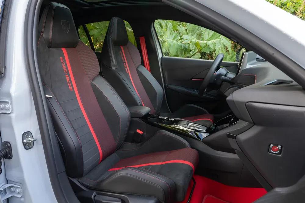 Intérieur sportif de la Peugeot 208 GTI avec sièges en cuir noir et rouge.