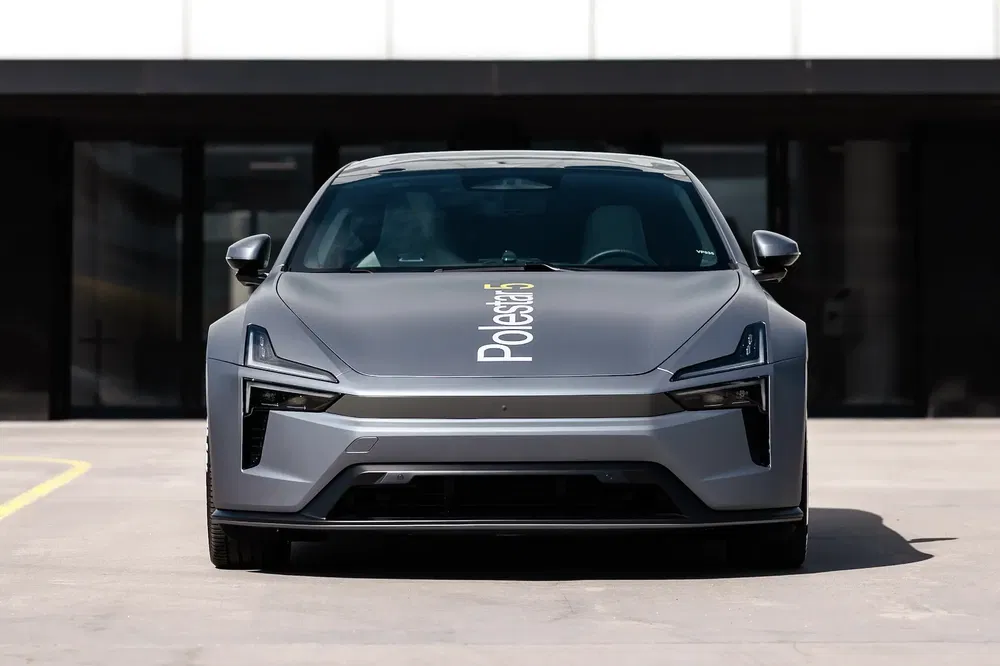 Voiture électrique Polestar 5 grise vue de face devant un bâtiment moderne.